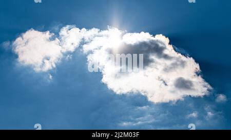 Die Sonne scheint hinter den Wolken am Himmel Stockfoto