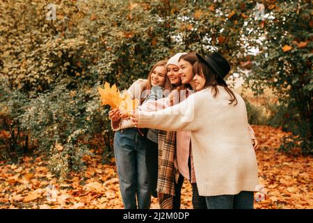 Vier enge Freundinnen Unternehmen Gruppe verbringen Zeit zusammen, hängen lachend im Herbst Golden Tree Naturpark Stockfoto