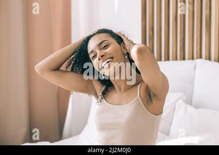 Nahaufnahme einer jungen afrikanerin, die im Bett sitzt, wachen Sie auf und Viel Spaß. Morgen positive Stimmung und Bewegung. Stockfoto