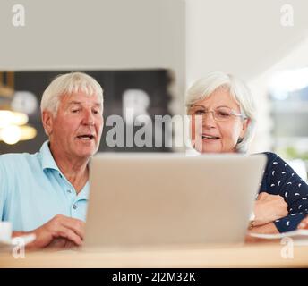 Wir können das kostenlose WiFi nutzen, um so ziemlich alles zu tun. Aufnahme eines älteren Paares, das zusammen einen Laptop benutzt. Stockfoto