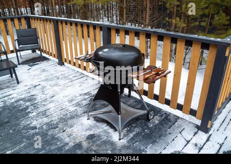 Barbecue-Grill auf der Terrasse eines Landhauses im Wald. Stockfoto