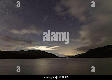 Ein Blick auf den Nachthimmel über Ullswater im englischen Lkae District in einer wolkigen Winternacht Stockfoto