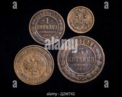 Alte russische Münzen aus dem 19.. Jahrhundert, Kupfergeld auf schwarzem Hintergrund. Draufsicht auf alte russische Münzen mit Monogramm und kaiserliches Wappen. Konzept Stockfoto