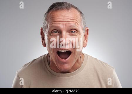 Ich kann das kaum glauben. Aufnahme eines hübschen reifen Mannes, der allein vor grauem Hintergrund im Studio steht und überrascht aussieht. Stockfoto