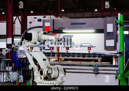 Roboterarm, der an der hydraulischen Biegemaschine mit Metallblech arbeitet. Stockfoto