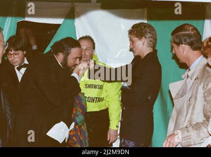 Der italienische Opernsänger Luciano Pavarotti küsst Prinzessin Diana die Hand, während Prinz Charles nach dem regnerischen Pavarotti im Park-Konzert im Hyde Park, London, aufwartet. Bild aufgenommen am 30.. Juli 1991. Stockfoto