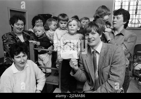 Der dreijährige Phillip Auckland überreicht einen £50-Scheck der Mutter- und Kleinkindgruppe Denby Dale an Dr. Michael Miller, Facharzt für Kinderheilkunde bei Huddersfield Royal Infirmary. Das Geld, das aus den Ausschussmitteln kam, wird denjenigen mit Mukoviszidose helfen. Die Mothers' and Toddlers' Group gibt außerdem £50 Schecks an den West Yorkshire Ambulance Service Heartbeat Appeal, um lebensrettende Ausrüstung für Herzinfarktopfer zu kaufen, und ein Kinderkrankenhaus in Sheffield, in dem eines der Kleinkinder wegen eines Nierenproblems behandelt wurde. 11.. April 1989. Stockfoto