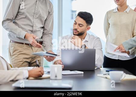 Jeder Plan muss zuerst von ihm genehmigt werden. Aufnahme eines jungen Geschäftsmannes, der in einem Büro mit seinen Kollegen diskutiert. Stockfoto