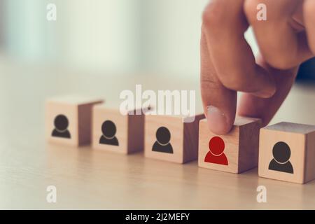 Personalmanagement, Rekrutierung und Zielkundengeschäft. Die Hand des Mannes setzt eine rote Person aus Holzwürfel, die auf der Menge mit Schwarz steht Stockfoto