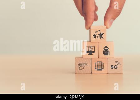 Neue futuristische Technologien für ein besseres Leben. Die Hand hält Holzwürfel mit Wohlfühlsymbol auf intelligenten Symbolen; Quantencomputing, automatisches Rob Stockfoto