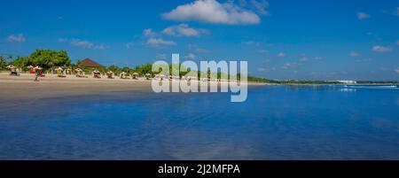 Sonnenschirme an einem heißen, sonnigen Tag mit Flut am Strand von Kuta, Bali, Indonesien. Stockfoto