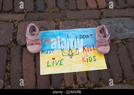 Schuhe auf einem Plakat mit der Aufschrift „Kinder müssen leben, tötet keine Kinder“ während des Protestes der ukrainischen ‘Art Installation“. Eine Kunstinstallation von Mitgliedern der ukrainischen Gemeinde in den Niederlanden wurde installiert, um die Aufmerksamkeit insbesondere auf die Regierung zu lenken. Die Installation hatte Schuhe in Reihen auf der Het Plain (Plain Square) im Stadtzentrum von Den Haag, um die Aufmerksamkeit auf das geistlose Gemetzel von Zivilisten und Kindern in der Ukraine zu lenken, als die russische Invasion in der Ukraine in der sechsten Woche begann. (Foto von Charles M Vella/SOPA Images/Sipa USA) Stockfoto