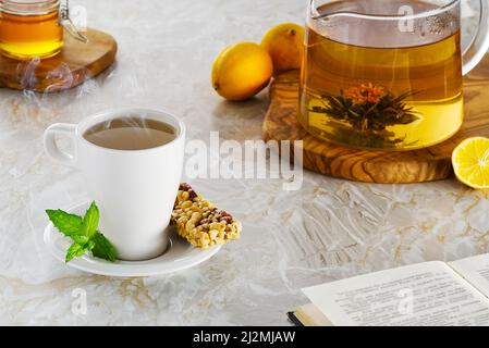 Tee heißes Getränk mit Dampf auf altem Hintergrund in Zusammensetzung auf dem Tisch Stockfoto