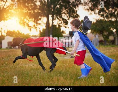 Bereit, Kriminalität zu bekämpfen. Aufnahme eines kleinen Jungen und seines Hundes, der Umhänge trägt, während er draußen spielt. Stockfoto