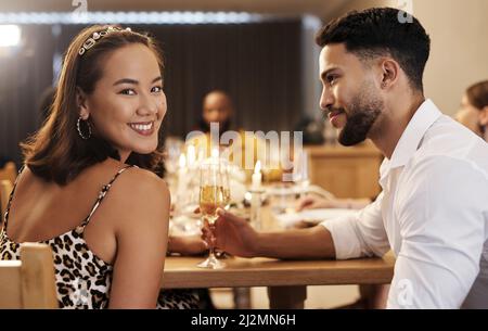 Wie habe ich so viel Glück gehabt? Aufnahme einer attraktiven jungen Frau, die mit ihrem Freund während einer Neujahrs-Dinner-Party sitzt. Stockfoto