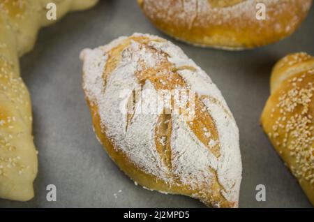 Schönes Sauerteigbrot auf grauem Hintergrund mit getrockneter Weizenblume. Stockfoto