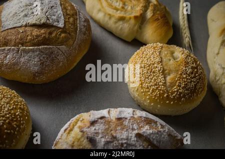 Schönes Sauerteigbrot auf grauem Hintergrund mit getrockneter Weizenblume. Stockfoto