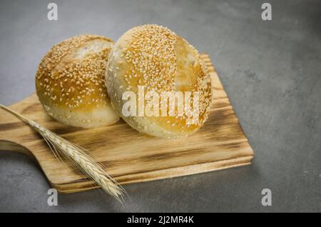 Schönes Sauerteigbrot auf grauem Hintergrund mit getrockneter Weizenblume. Stockfoto