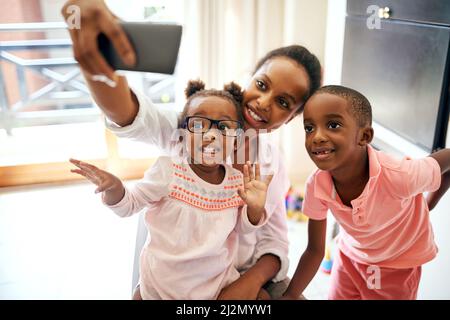 Glückliche Momente festhalten. Eine kurze Aufnahme einer liebevollen jungen Familie, die zu Hause Selfies macht. Stockfoto