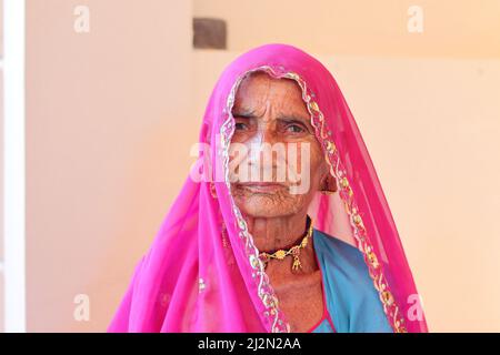 Pali Rajasthan, Indien - 23. Oktober 2021. Nahaufnahme eines Porträts einer älteren indischen Frau, die in einem rosa roten Schleier sitzt. Indianerdorf Stockfoto