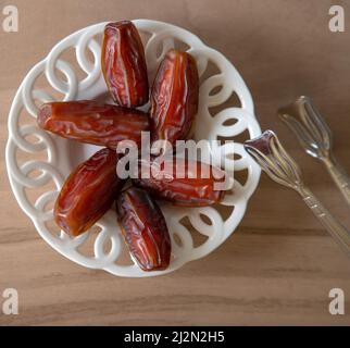 Schale mit Datteobst auf Holzhintergrund Stockfoto