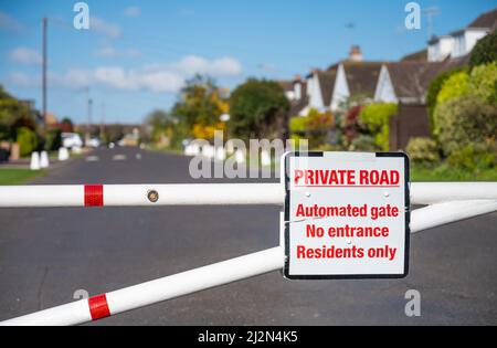 Eingezäunter Eingang mit geschlossenem Tor zu einer Privatstraße in der Cudlow Avenue, Rustington, West Sussex, England, Großbritannien. Stockfoto