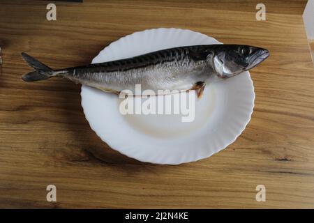 Makrelenfisch liegt auf einem weißen Teller auf dem Tisch. Hausmannskost. Stockfoto