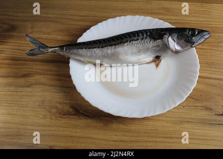 Makrelenfisch liegt auf einem weißen Teller auf dem Tisch. Hausmannskost. Stockfoto