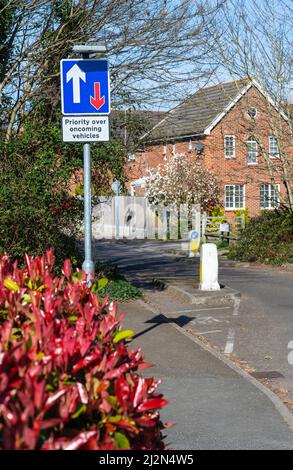 Priorität vor entgegenkommenden Fahrzeugen Straßenschild, wo die Straße aufgrund von Maßnahmen zur Verkehrsberuhigung auf einer Straße in England, Großbritannien, enger wird. Stockfoto