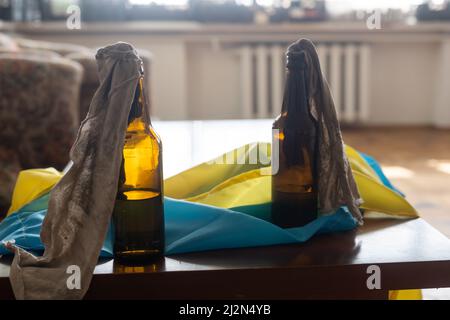 Molotow Cocktail, Kriegsrecht in der Ukraine, eine brennbare Mischung in Flaschen mit einem Lappen liegt auf der Flagge der Ukraine, Krieg Ukraine 2022 Stockfoto