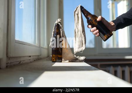 Glasflasche, gefüllt mit Benzin, einem sogenannten Molotow-Cocktail, auf dem Fenster im Haus Stockfoto
