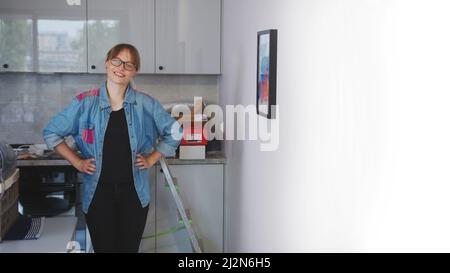 Stolze weibliche europäische Kleinunternehmerin, die das Haus ihres Kunden ganz allein mit professionellen Werkzeugen schmückt. . Hochwertige Fotos Stockfoto