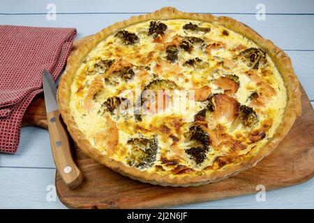 Nahaufnahme eines ganzen Brokkoli-Lachs-Pie auf einem Holzbrett Stockfoto