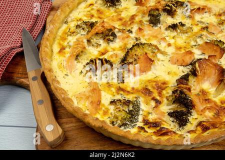 Nahaufnahme eines ganzen Brokkoli-Lachs-Pie auf einem Holzbrett Stockfoto