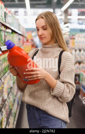 Junge Frau wählt Conditioner oder ein Waschgel im Laden. Stockfoto