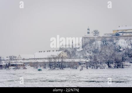 Novi Sad, Serbien - 23. Januar 2014: Festung Petrovaradin vom Ufer der Donau im Winter durch Nebel. Stockfoto