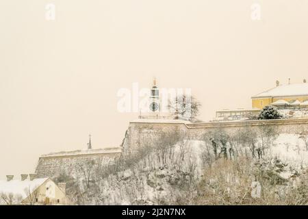 Novi Sad, Serbien - 23. Januar 2014: Festung Petrovaradin vom Ufer der Donau im Winter durch Nebel. Stockfoto