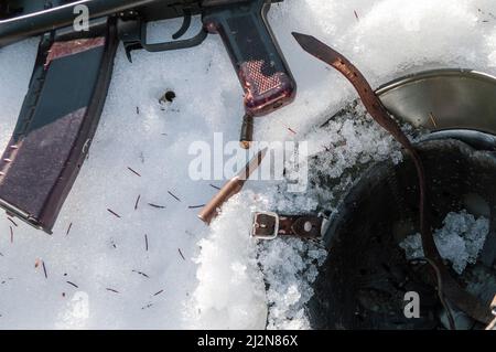 Nahaufnahme von verlassenen auf dem Schnee Kampfhelm und Maschinengewehr mit verstreuten Kugeln Stockfoto