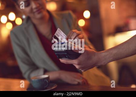 Wischen Sie einfach darüber. Nahaufnahme einer jungen Frau, die ihre Kreditkarte strüpft, um eine Zahlung in einem Café zu tätigen. Stockfoto