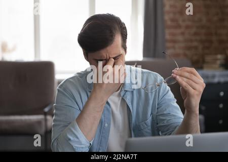 Frustrierte Mitarbeiter, die im Heimbüro am Laptop arbeiten Stockfoto
