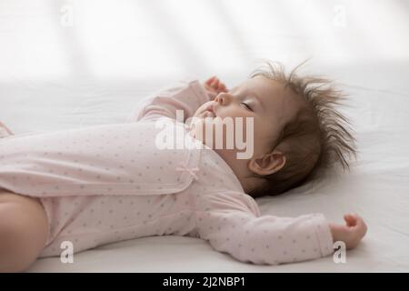 Friedliche Ruhe, ruhig, ruhig, süß, Baby-Mädchen, das einen rosa Bodysuit trägt Stockfoto