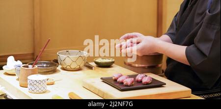 Küchenchef bereitet traditionelles Thunfisch-Sushi im Restaurant zu. Omakase Dining Atmosphäre. Stockfoto