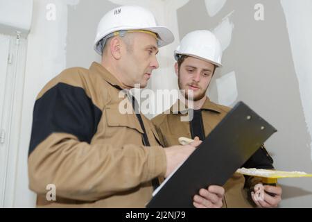 Bauarbeiter beraten Pläne in neuem Haus Stockfoto