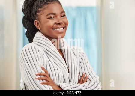 Es ist Zeit für meine Hautpflege-Routine. Aufnahme einer schönen jungen Frau, die zu Hause in ihrem Bademantel steht. Stockfoto