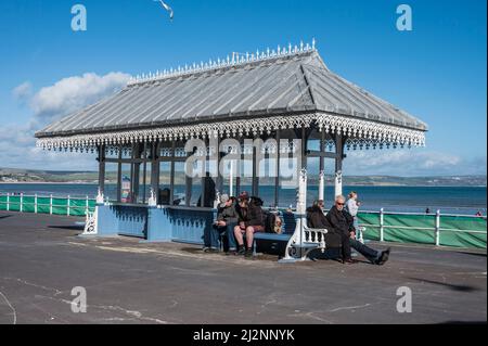 Bunte Szenen von Urlaubern, die sich auf der Esplanade-Promenade von Weymouth mit Blick auf die Weymouth Bay entspannen Stockfoto