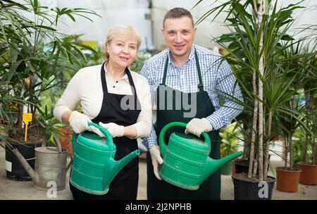 Zwei Gärtner kümmern sich um Blumen und bewässerten sie Stockfoto
