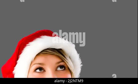 Wir feiern die festlichsten Jahreszeiten. Aufnahme einer Frau, die einen Weihnachtshut vor einem Studiohintergrund trägt. Stockfoto