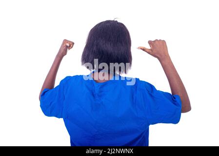 Schöne junge Ärztin in blauer Uniform, die von hinten steht und ihren Daumen zeigt. Stockfoto