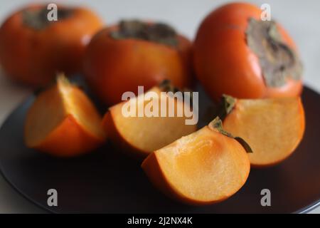 In Scheiben geschnittener Amarphal. Persimmon oder Amarphal ist eine Frucht aus Japan, China, Korea, Burma, Nepal und einigen Teilen Indiens. Tieforange Farbe Frucht Witz Stockfoto