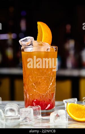 Tequila Sunrise Cocktail (oder ähnlich, zum Beispiel Jagermonstr) mit Tequila, Grenadine und Orangensaft an der Bar. Stockfoto